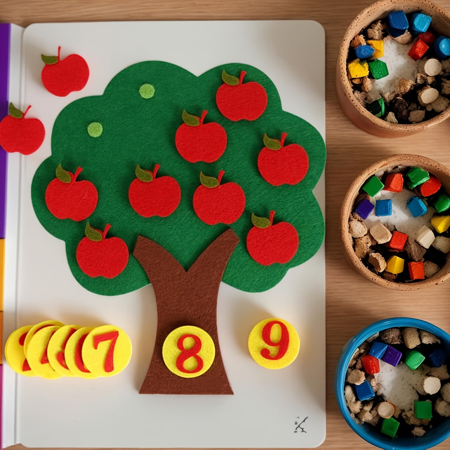 Enfant manipulant les chiffres et les pommes sur le tableau en feutrine.